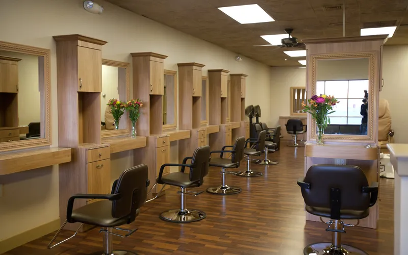 A row of styling stations down one wall, each with a framed mirror and a vase of fresh flowers.