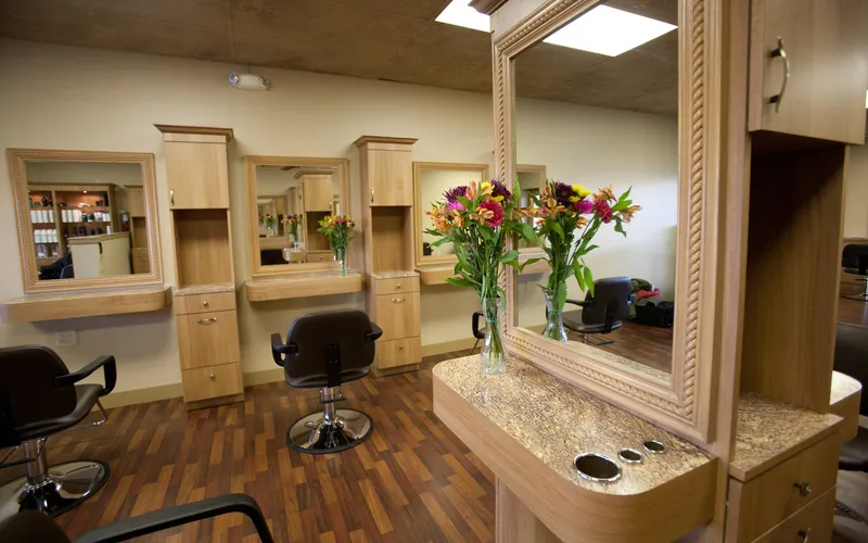 A granite-topped styling station with flowers, with further stations and mirrors beyond it.