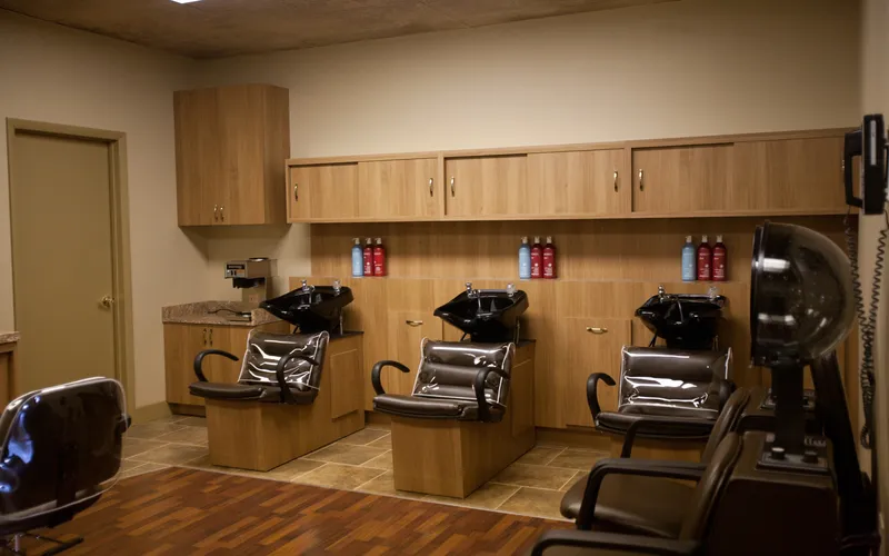 The shampoo area: three black basins with reclining chairs, and a hooded dryer to one side.