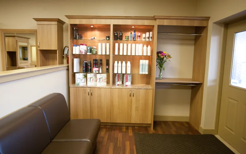 The waiting area, with a bench beside a lit cabinet displaying hair care products.